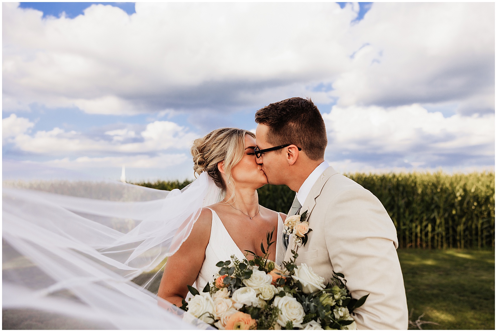 Newlyweds kiss as the veil blows in the wind around them at a sable creek homestead wedding